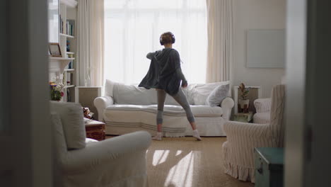 happy young woman dancing at home having fun listening to music wearing headphones enjoying weekend celebration with funky dance moves