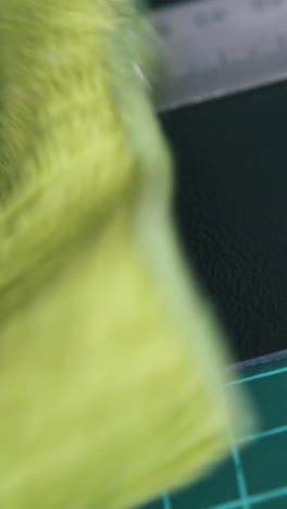 cu: person hand cleans black leather fabric with special yellow wet towel near metal ruler extreme close view