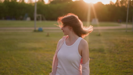 Woman-in-comfortable-clothes-shakes-loose-hair-on-meadow