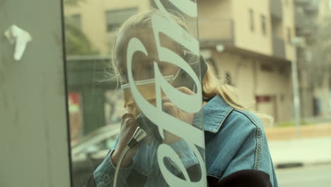 woman in mask speaking on telephone on street