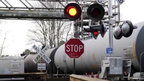active railroad crossing sign with train passing in the background.