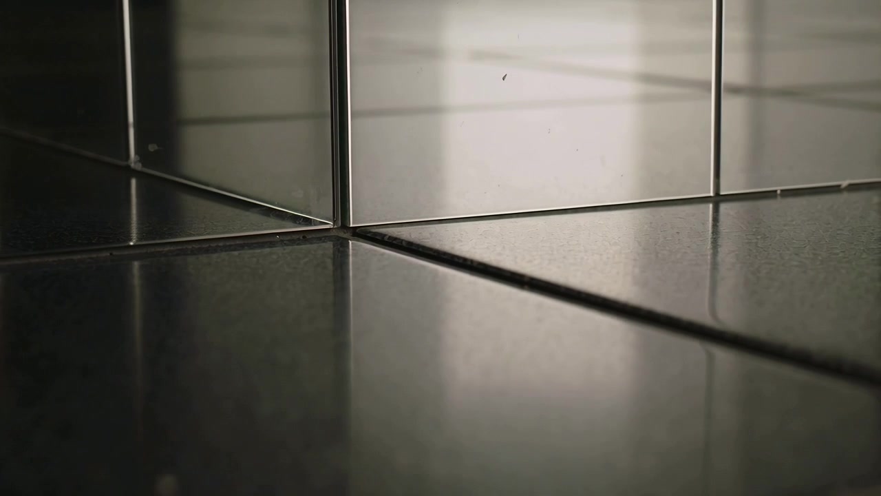 Câmera deslizando e revelando canto de azulejo encontrando espelhos em penteadeira, enquadrando reflexo de janela com poeira de rejunte