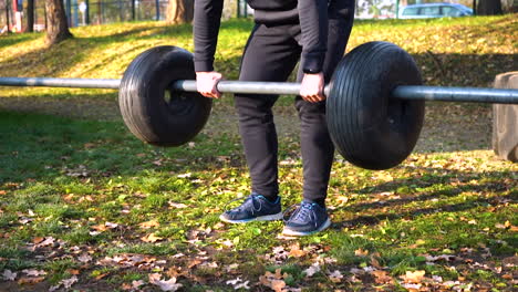 guy doing deadlift with a metal bar and tires,park in autumn,czechia