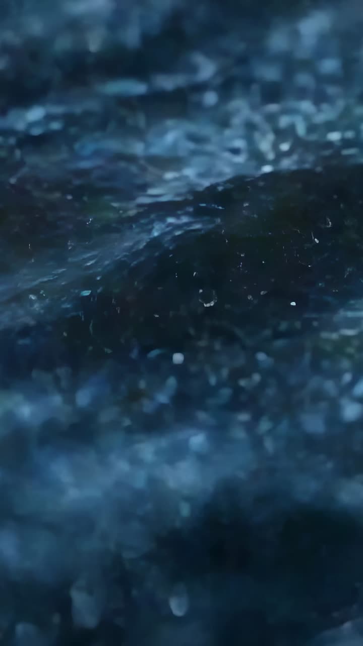 Video verticale: Acqua blu increspata che riceve gocce di pioggia al tramonto, formando goccioline, spruzzi e riflessi.