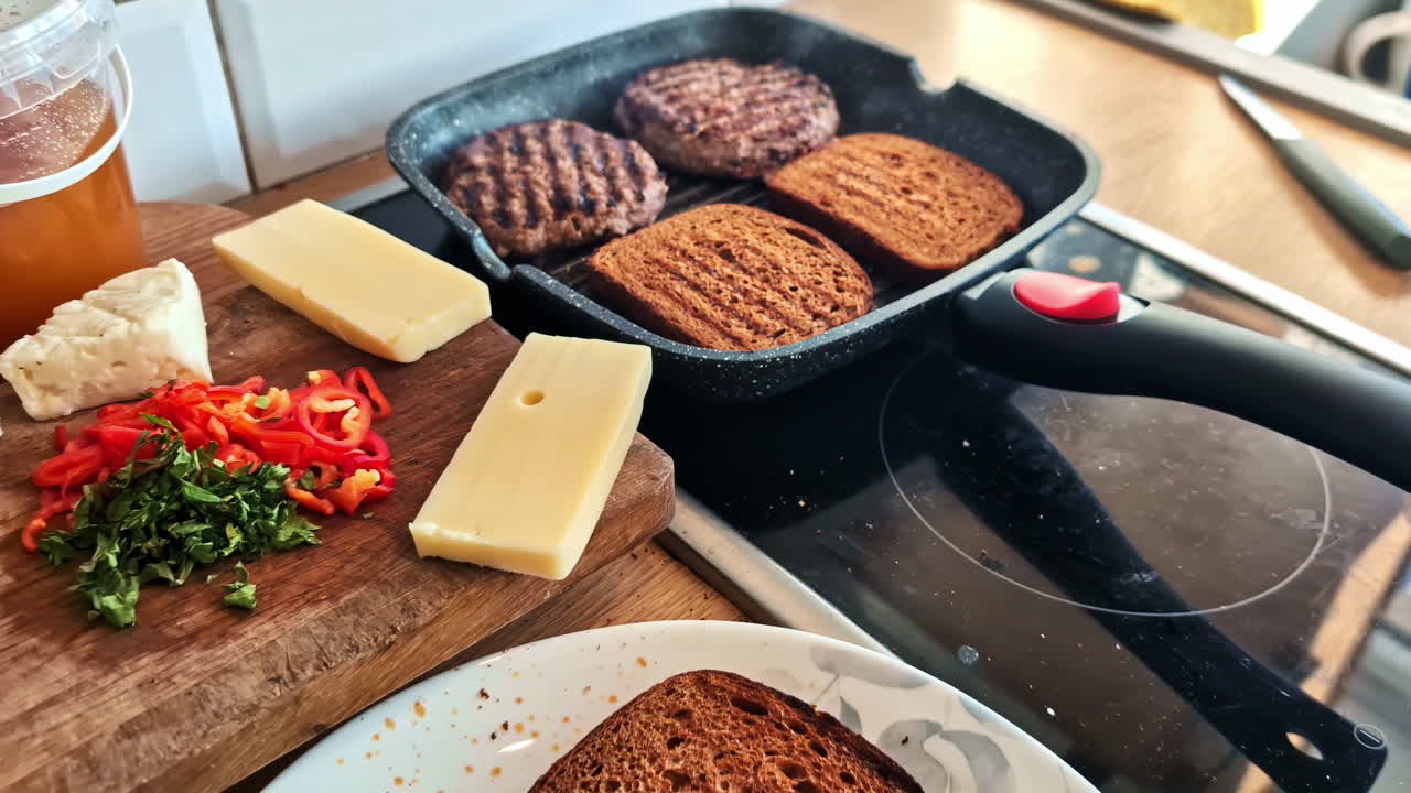 Zoomed-out view of meat and bread cooking in pan, with cheese and vegetables on plate.