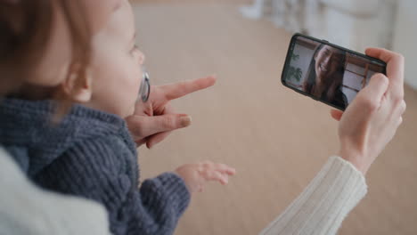 mother and baby using smartphone having video chat with best friend waving at toddler happy mom enjoying sharing motherhood lifestyle on mobile phone screen