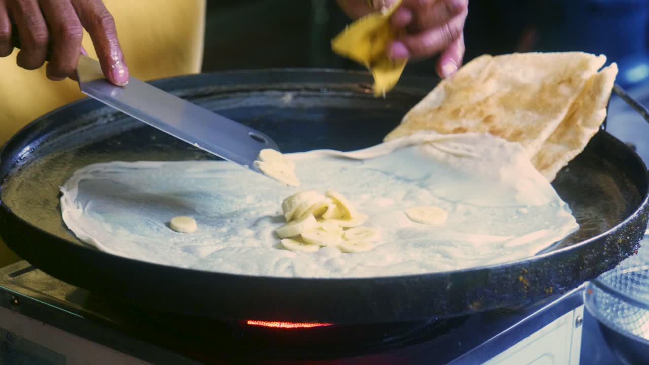 imágenes cinematográficas de cocina de 4k de un chef tailandés preparando un postre tradicional tailandés llamado roti en un mercado callejero en tailandia