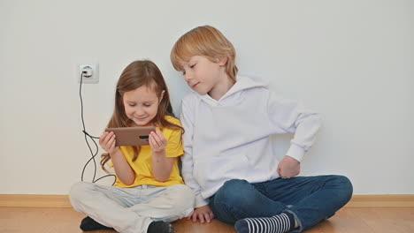 little boy and girl using a smartphone and watching online videos at home