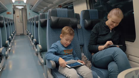 familia viajando en tren y entreteniéndose con electrónica