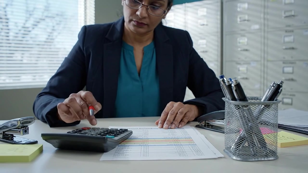 Contador Focado Analisando Dados Financeiros com Calculadora e Documentos em um Ambiente de Escritório Moderno, Demonstrando Profissionalismo e Concentração