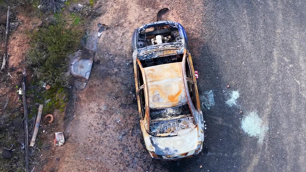 Ripresa aerea con drone di un veicolo carbonizzato e arrugginito abbandonato nella foresta di Goonoo, Australia.