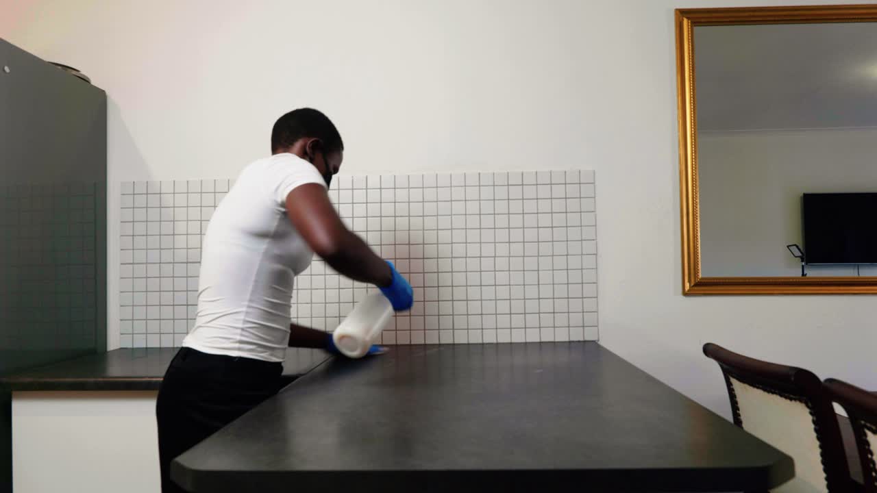 African lady cleaning disinfect kitchen counter top during Covid