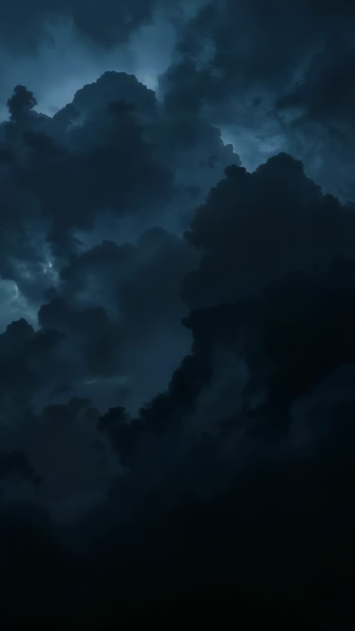 Vertical video: Wind reshaping storm cloud forming glowing veins at night, with lightning flashes