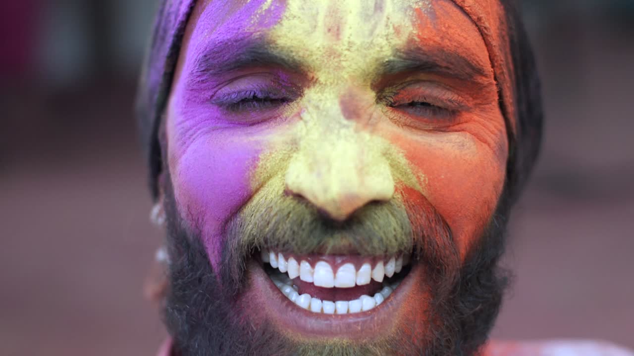 Indian man close-up of face smeared with bright Holi colors