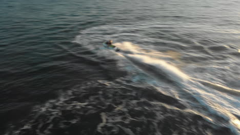 una mujer realiza giros cerrados en una moto de agua en un océano abierto durante una hermosa puesta de sol