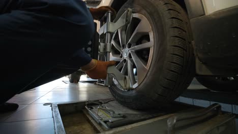 auto mechanic installing sensor during suspension adjustment and automobile wheel alignment work at repair service station. close up