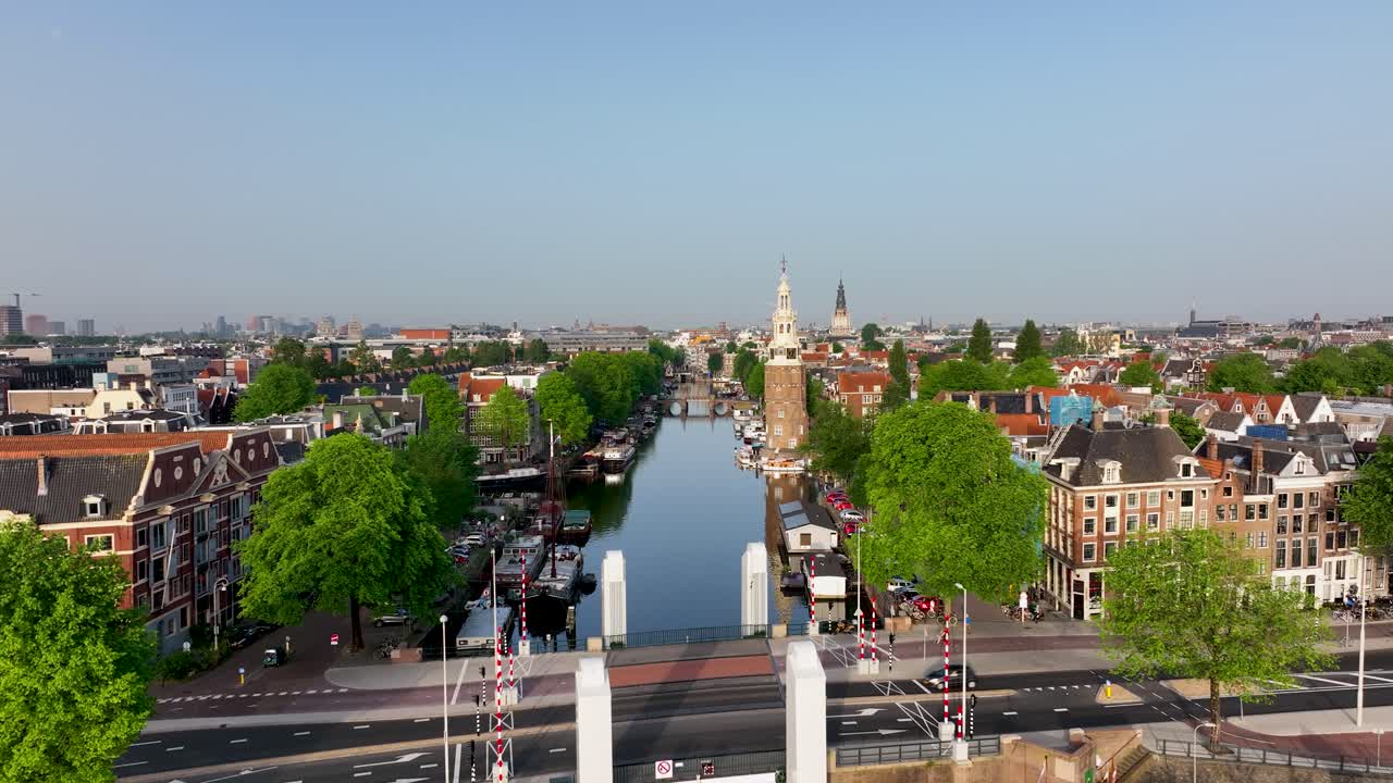 Scenic drone footage of Montelbaanstoren with boats and a bridge over the canal in Amsterdam