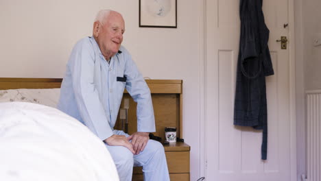 elderly man in pajamas sitting on bed