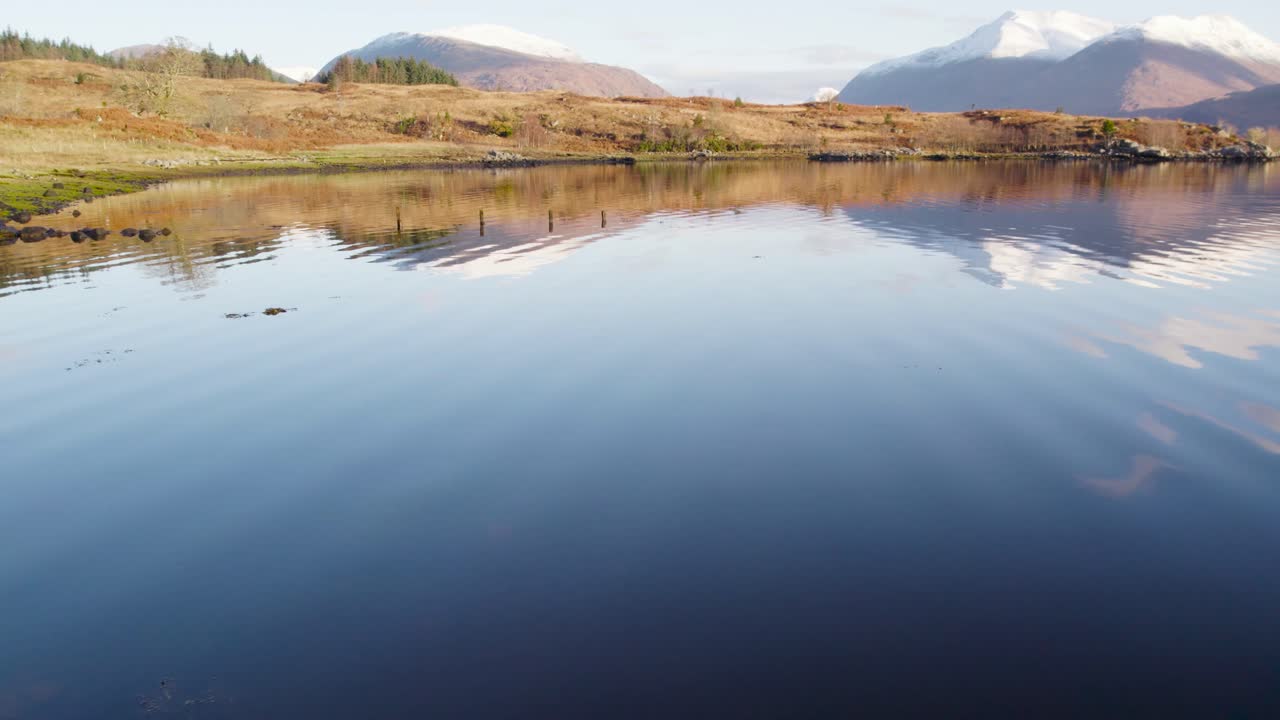imágenes aéreas de drones volando bajo y cerca de la orilla del lago etive