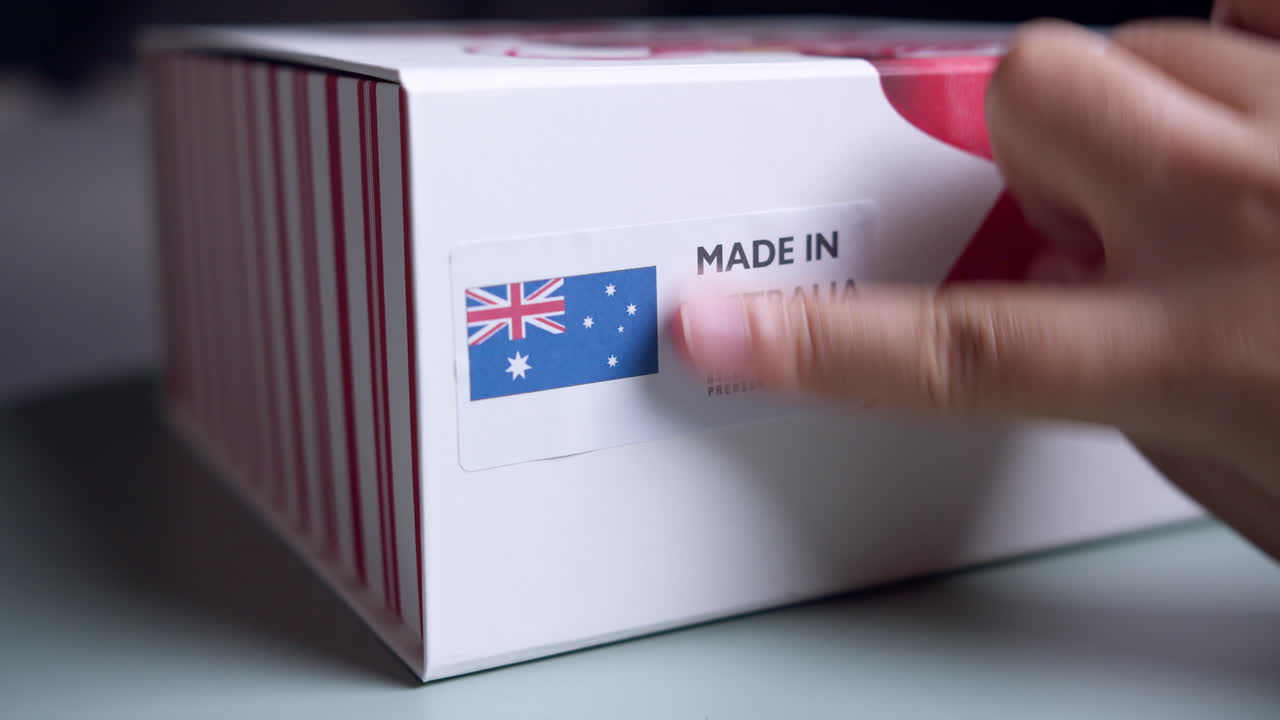 제품이 있는 배송 골판지 상자에 호주 국기 라벨로 만든 손 적용