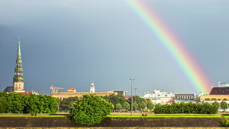 Skyline-of-Riga-city-with-majestic-colorful-rainbow-above,-fusion-time-lapse-view