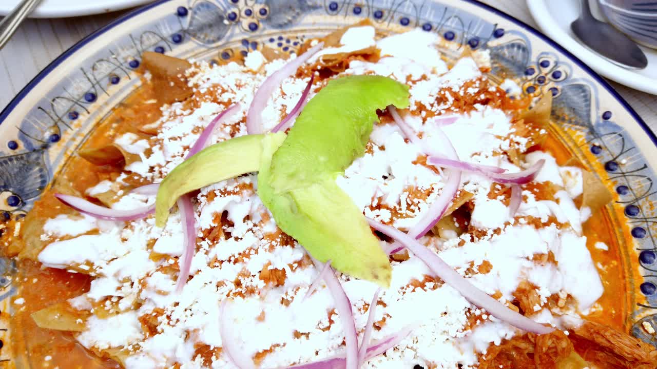 Piatto messicano chilaquiles con avocado e formaggio su un piatto festivo.