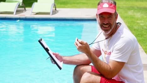 lifeguard sitting at pool side holding clipboard and stop watch