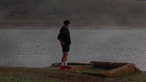 resting runner looks over misty lake, peaceful and reflective early morning moment