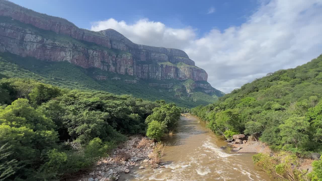 Panoramica su un fiume in piena fangoso che scorre lungo un'ampia valle africana