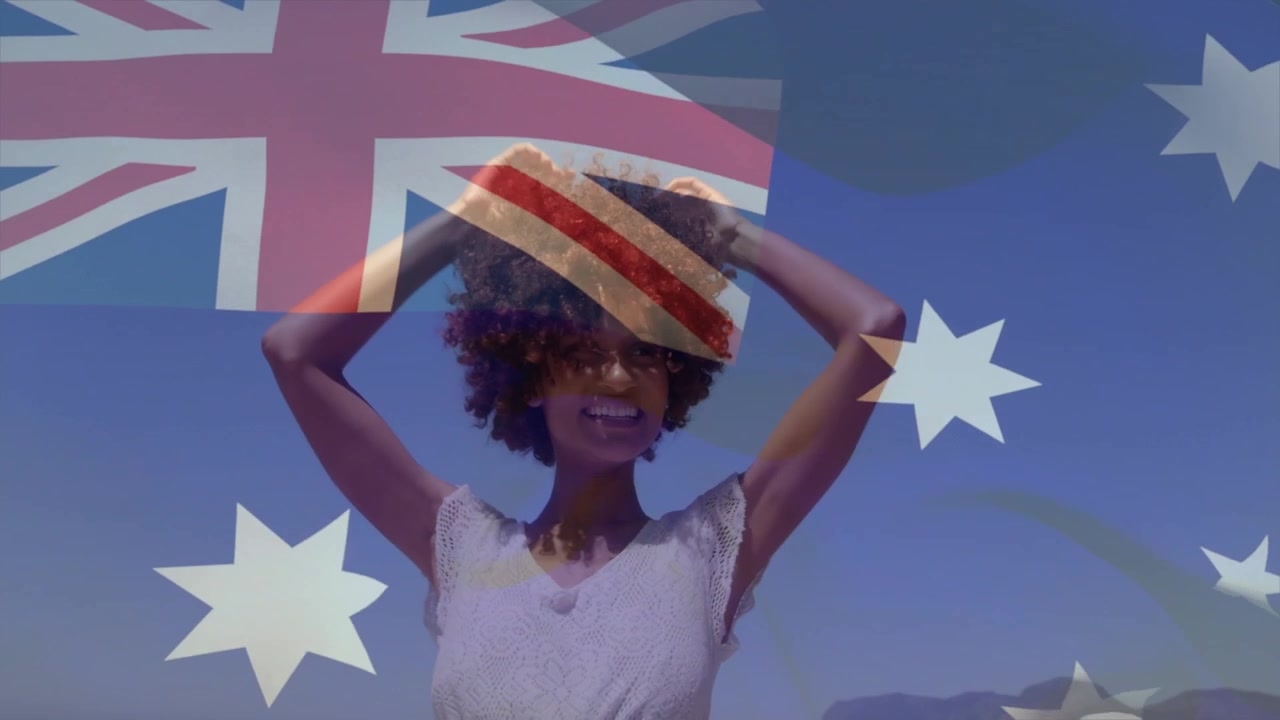 Donna che cammina sulla riva, provocando una panoramica verso l'alto, girandosi, alzando le braccia e le mani, con la bandiera australiana sovrapposta per il viaggio.