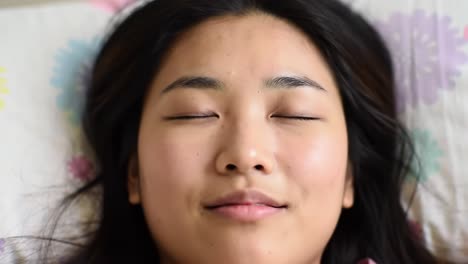Serene Close-Up of a Resting Woman with Eyes Closed, Suggesting Peacefulness and Relaxation in a Comfortable Bedroom Setting