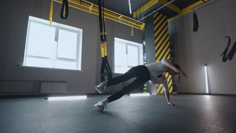 doing trx exercises. young athletic woman in sports clothing training legs with trx fitness straps in the gym. exercise where stabilizing muscles trained and the whole body is working truly functional