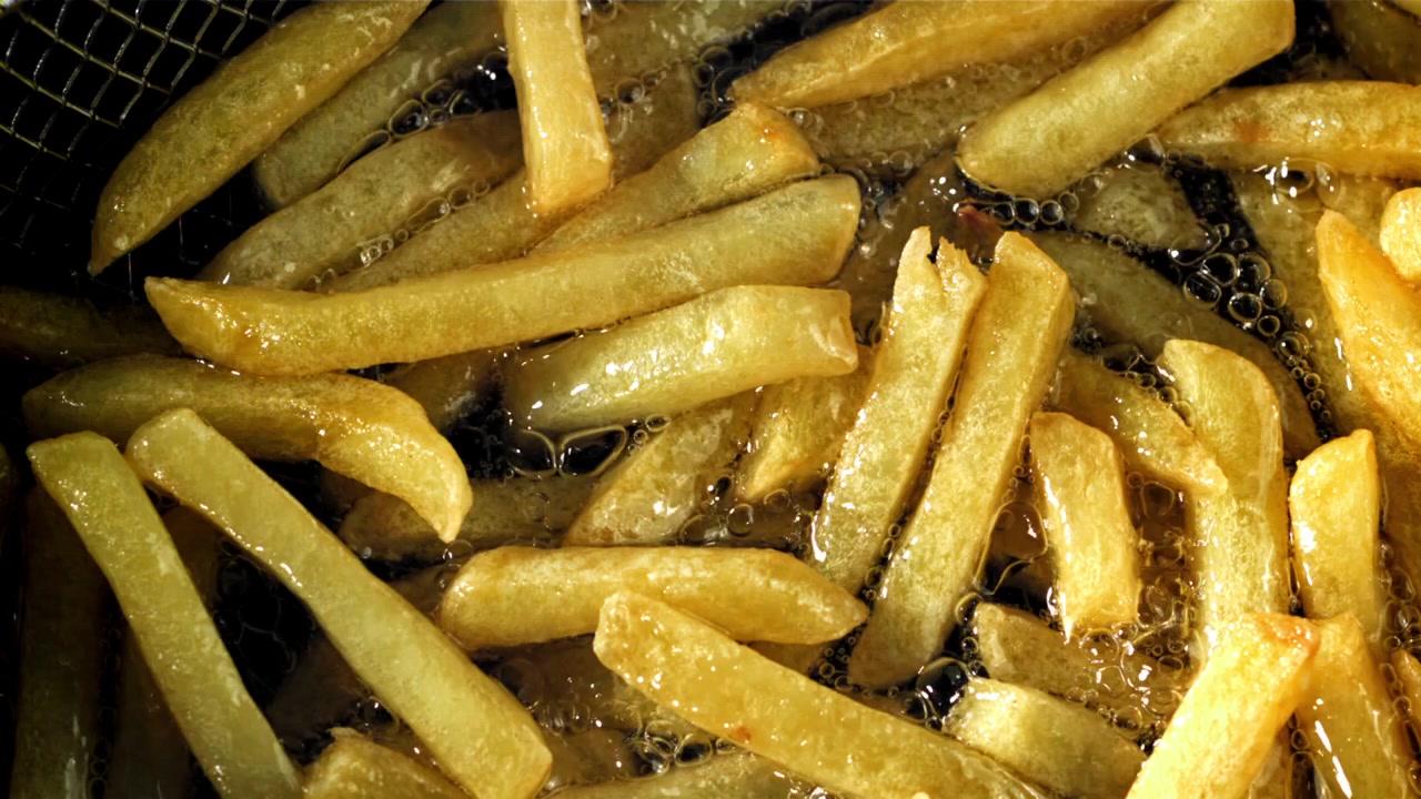 Batatas fritas douradas fritando em óleo quente borbulhante