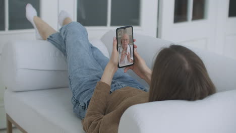 Young-Girl-Sick-at-Home-Using-Smartphone-to-Talk-to-Her-Doctor-via-Video-Conference-Medical-App.-Woman-Has-Conversation-with-Professional-Physician-Using-Online-Video-Chat-Application