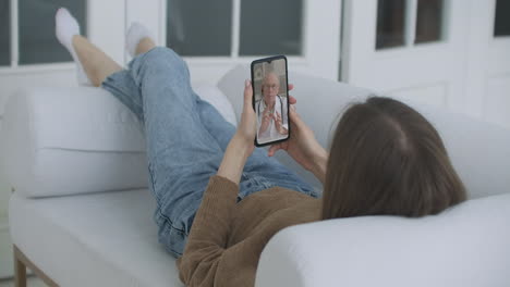 Niña-Enferma-En-Casa-Usando-Un-Teléfono-Inteligente-Para-Hablar-Con-Su-Médico-A-Través-De-Una-Aplicación-Médica-De-Videoconferencia.-La-Mujer-Tiene-Una-Conversación-Con-Un-Médico-Profesional-Usando-Una-Aplicación-De-Video-Chat-En-Línea