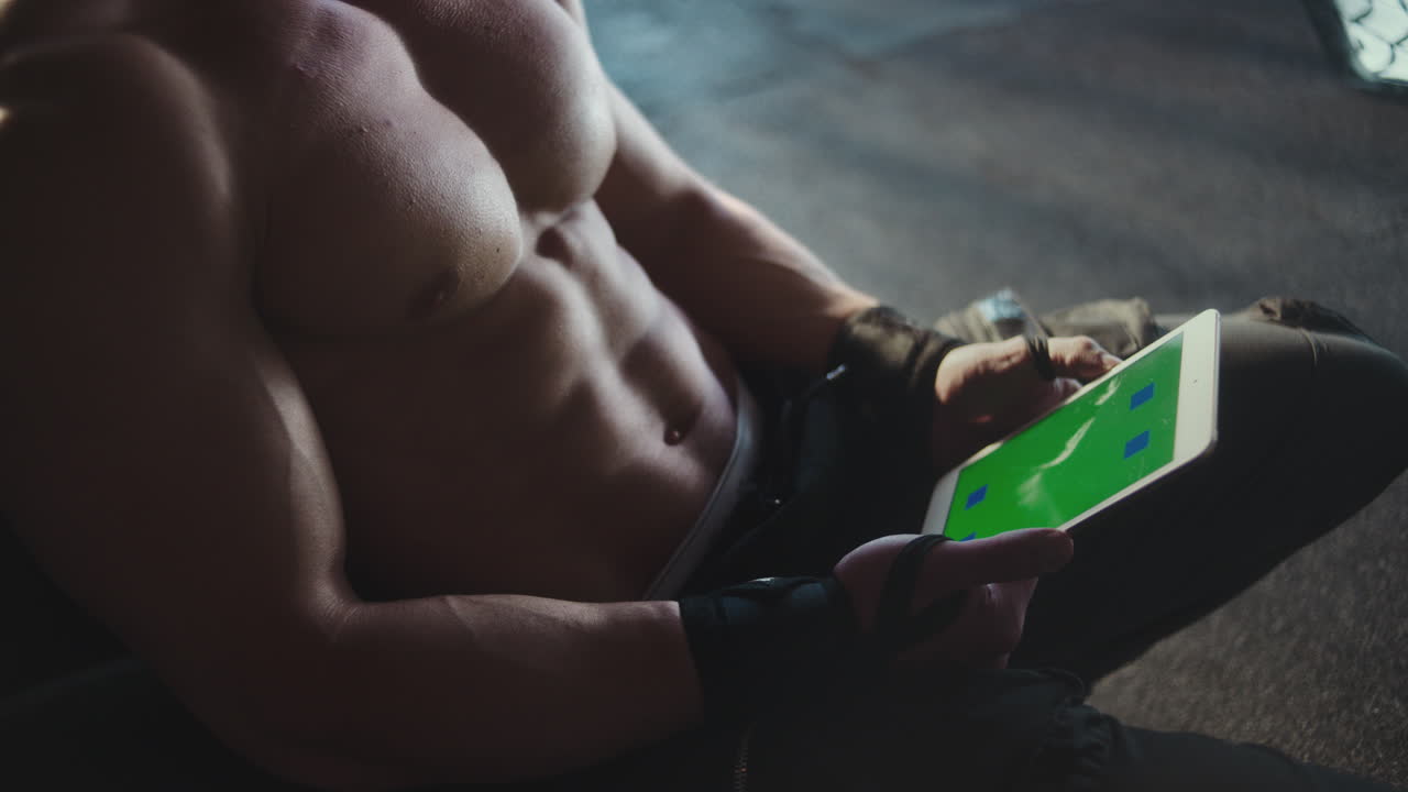 Muscular Man Using Tablet in Gym