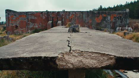 abandoned roofless cement structure in a field of serrated tussock grass static detail shot