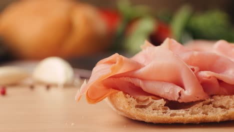 mortadella ham sandwich, traditional italian focaccia filled with thin pesto slices of mortadella, served by chef man in cafe restaurant. macro of traditional italian spanish tapas antipasti.