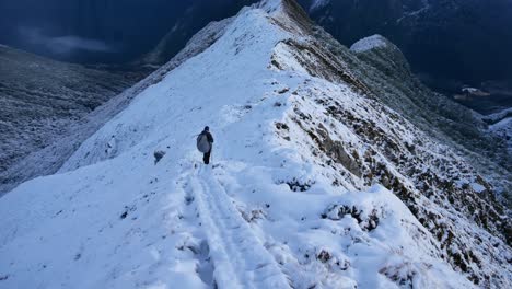 hiker crosses an mountain awe-inspiring snowy ridge on the kepler trek hike in new zealand, fiordland