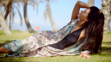 pretty woman in summer dress resting on grassy