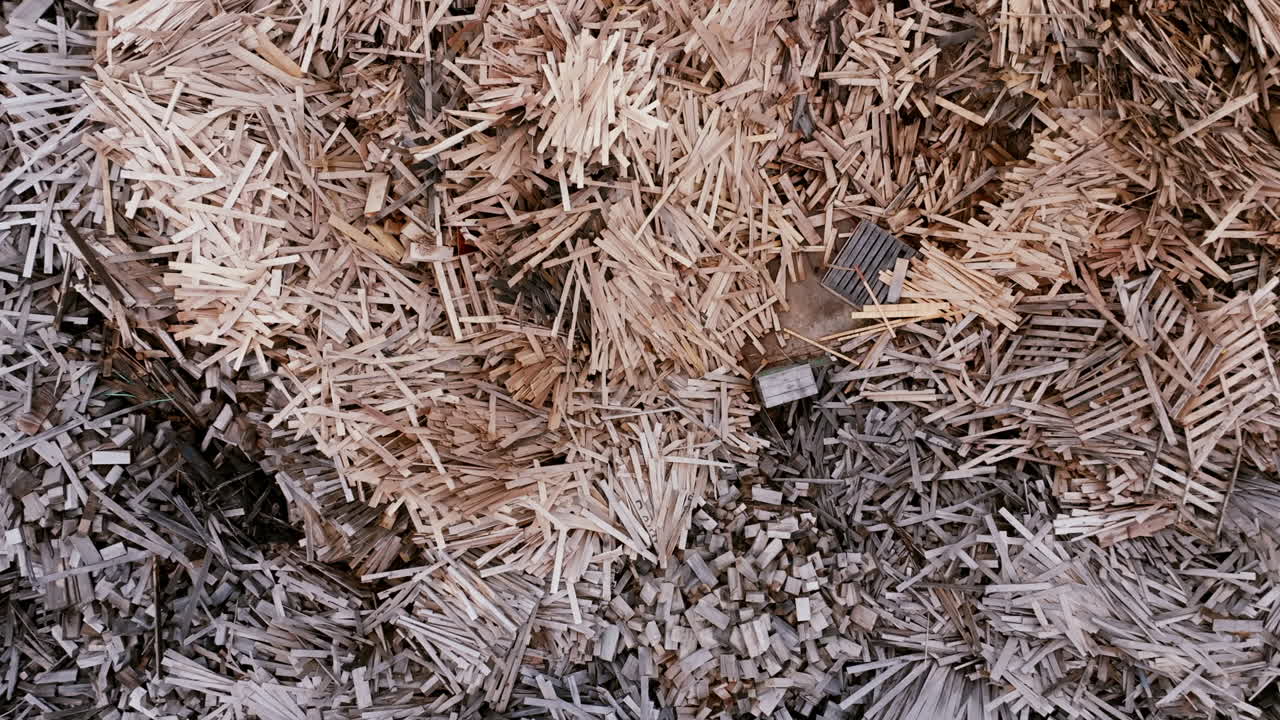 Top down aerial footage panning across gigantic piles of various wood materials.