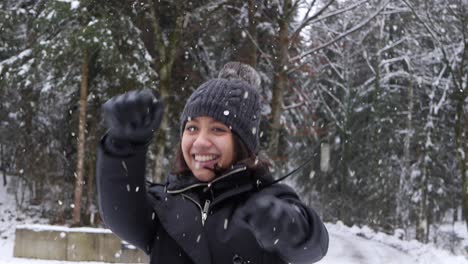 happy woman smiling and jumping in forestry area while snowing, close up view