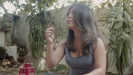 Medium-shot-of-Japanese-woman-burning-palo-santo-in-backyard