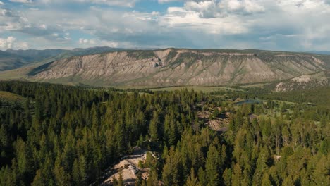 Stunning-aerial-drone-reveal-of-Montana-mountains-and-tree-filled-forest-landscape-on-blue-sky-cloudy-day-in-the-summertime