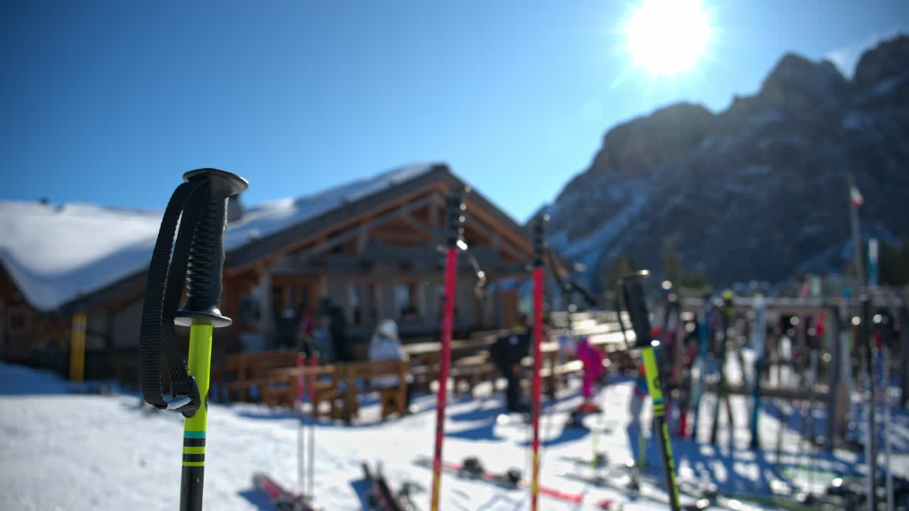Close up of ski poles and equipment gathered at a ski resort with the mountains in the background