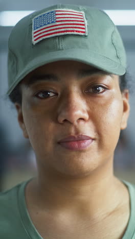 Portrait-of-female-soldier,-United-States-of-America-elections-voter.-Woman-in-camouflage-uniform-stands-in-polling-station-and-looks-at-camera.-Background-with-voting-booths.-Concept-of-civic-duty.