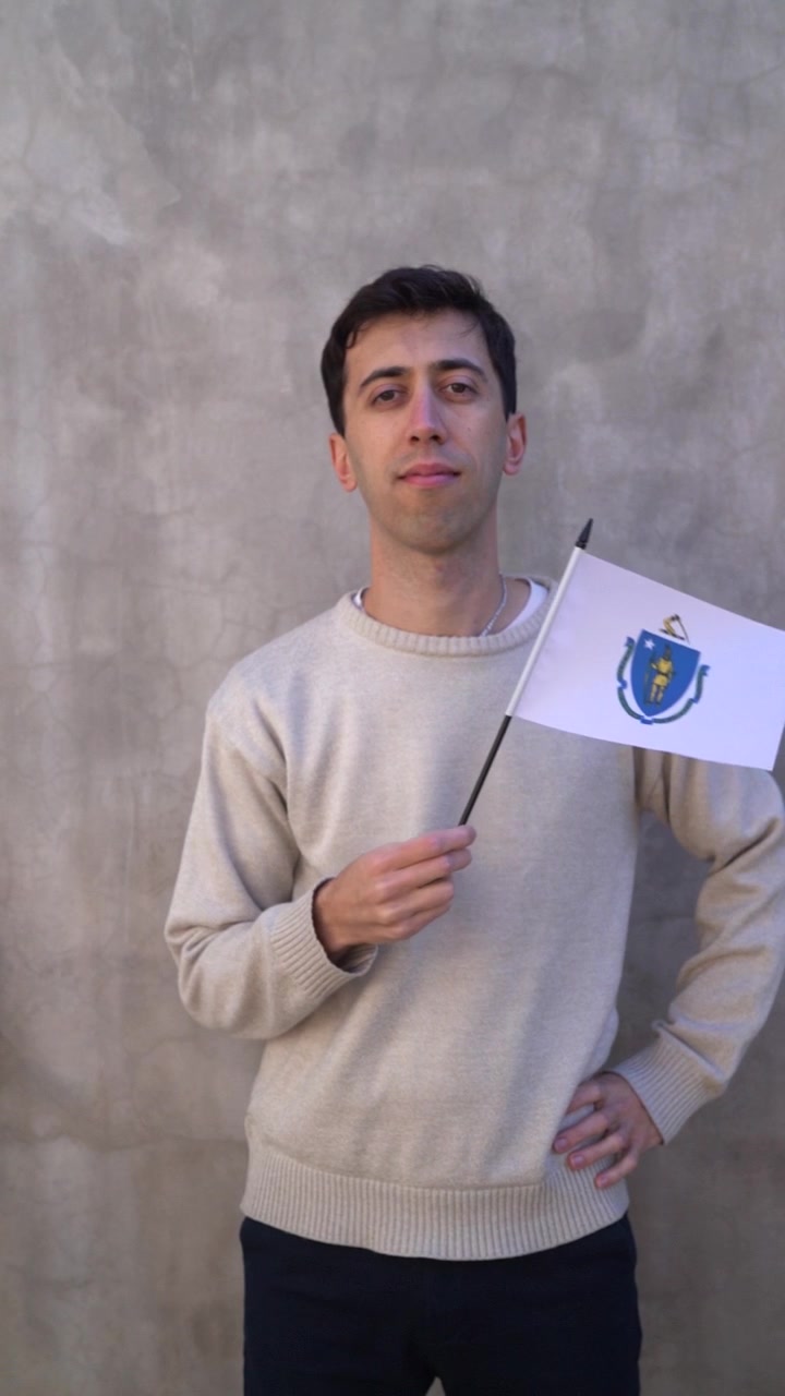 Ripresa verticale di un uomo bianco che sventola la bandiera dello stato del Massachusetts al rallentatore