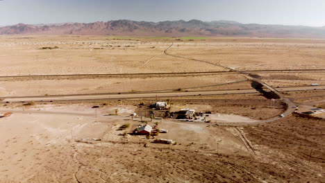 Aerial-view-of-a-long-straight-highway-stretching-through-a-barren-dessert-on-a-sunny-day