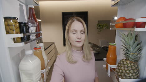 a middle-aged woman puts food in the refrigerator. view from inside the refrigerator