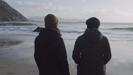 two people watching waves coming in on shore of achill island